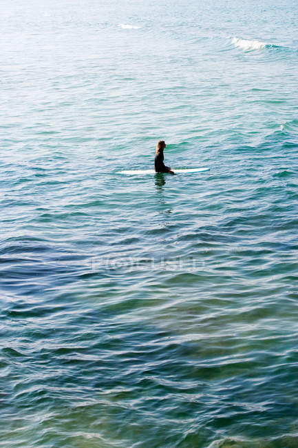 Woman sitting on surfboard in the water — Stock Photo