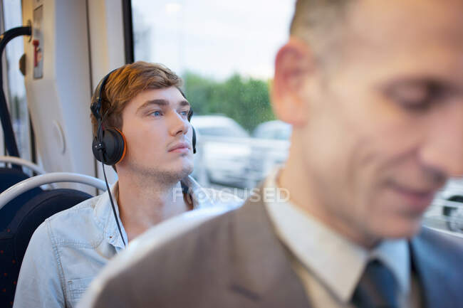 Young man listening to headphones on train — Stock Photo