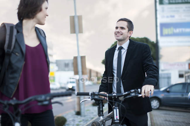 Young woman chatting to businessman whilst cycling to work — Stock Photo