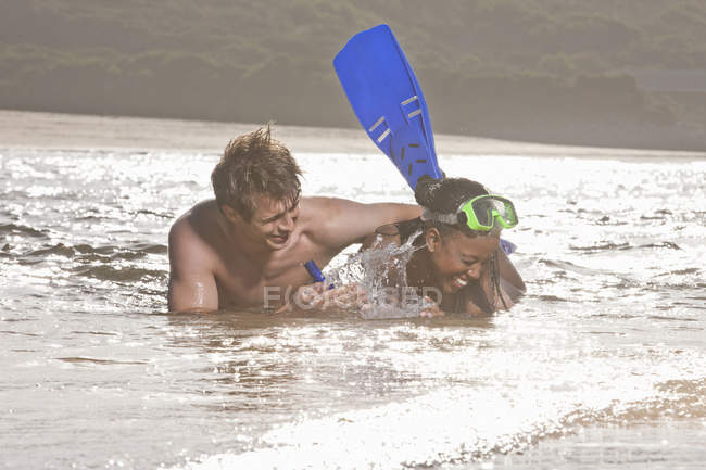 Junges Paar liegt im Meerwasser, trägt Schnorchel und lacht — Stockfoto