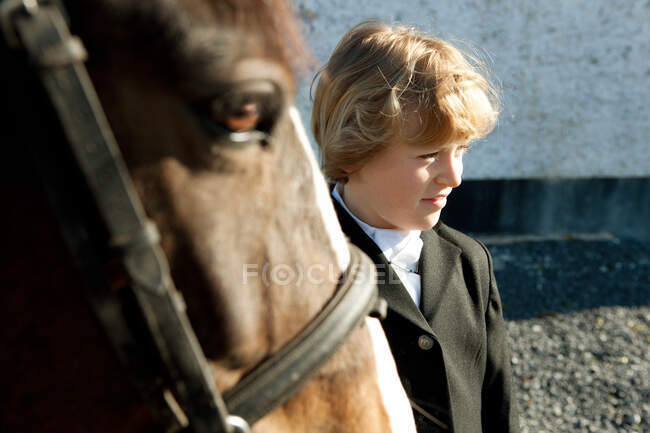 Niño de pie con caballo - foto de stock
