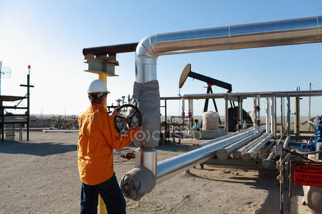 Працівник регулює труби на нафтовому родовищі — стокове фото