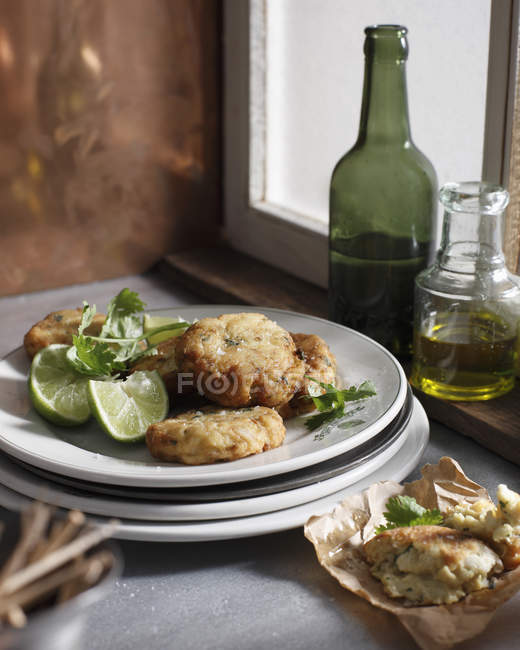 Crab cakes with lime slices on plate — Stock Photo