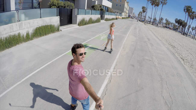 Visão traseira do casal de patinadores levando selfie, Venice Beach, Califórnia, EUA — Fotografia de Stock
