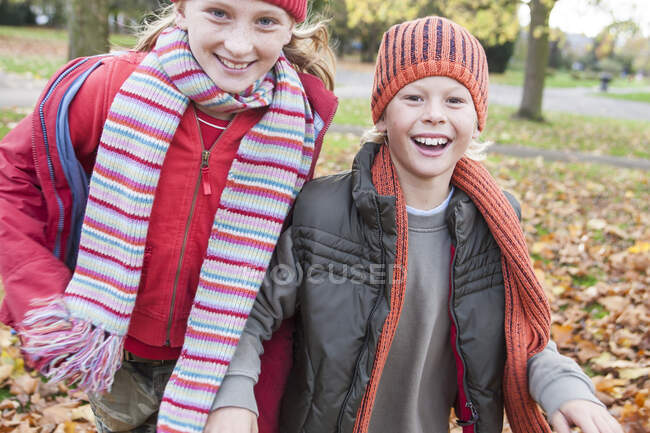 Брат и сестра прогуливаются по парку, улыбаясь — стоковое фото