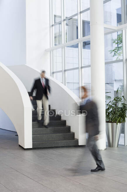 Hommes d'affaires en mouvement dans l'atrium de bureau — Photo de stock