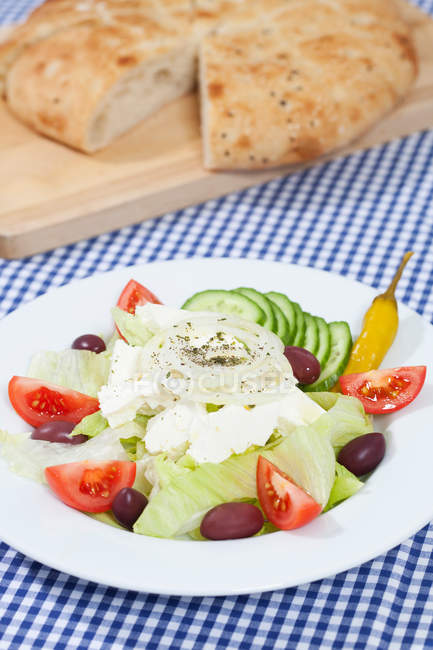 Тарілка грецького салату з хлібом на столі — стокове фото