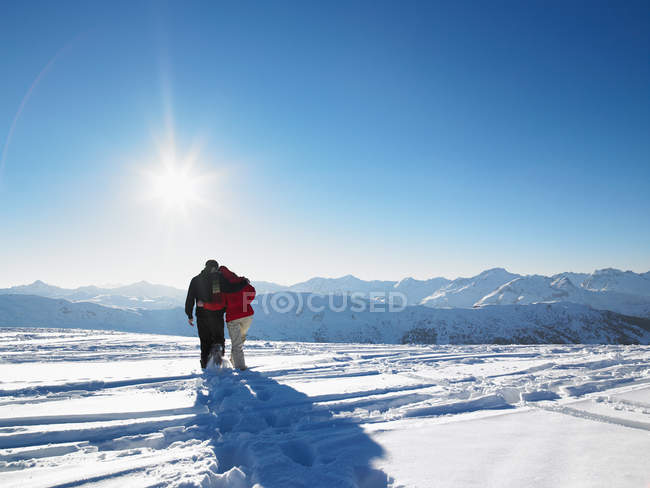 Vista trasera de pareja caminando en la nieve en la cima de la montaña - foto de stock