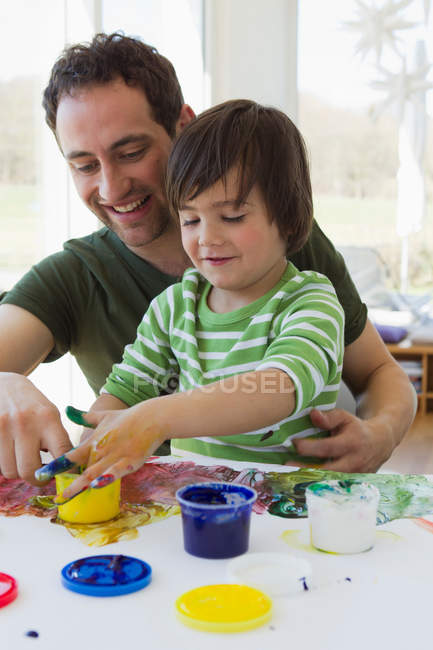 Отец и сын рисуют пальцами вместе — стоковое фото