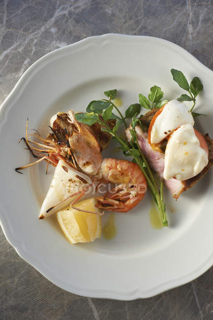Тарелка с морепродуктами, гарниром из трав и ломтиком лимона — стоковое фото