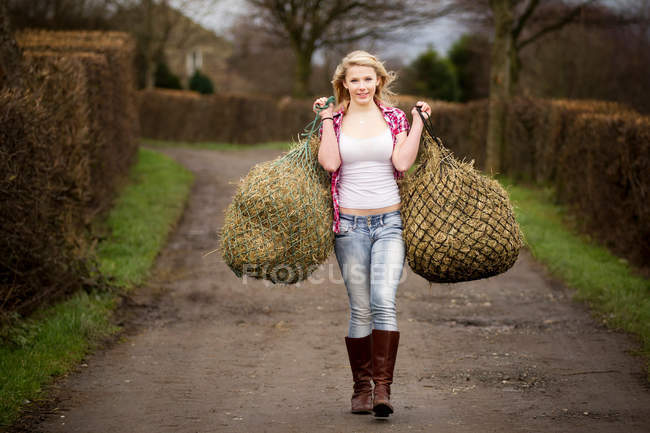 Ragazza adolescente che trasporta fieno sul sentiero sterrato — Foto stock