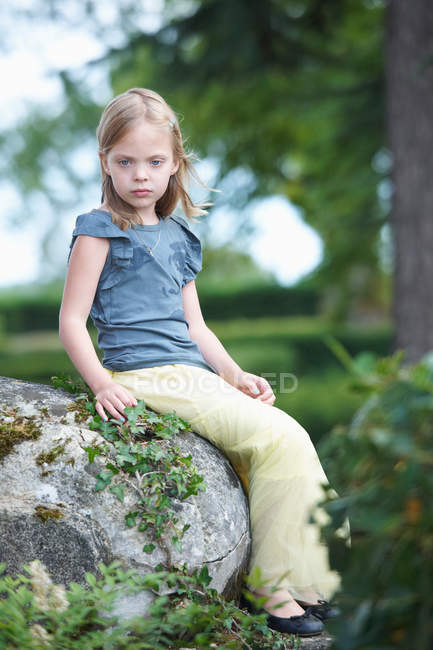 Menina sentada no rock ao ar livre, foco em primeiro plano — Fotografia de Stock