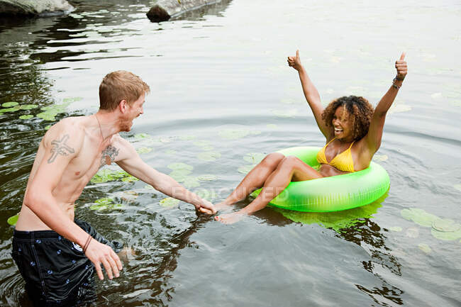 Couple playing on inflatable ring on lake — Stock Photo