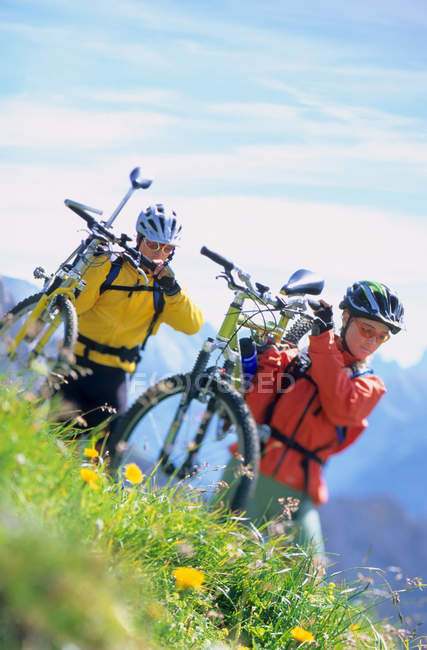 Ciclistas de montaña llevando sus bicicletas - foto de stock