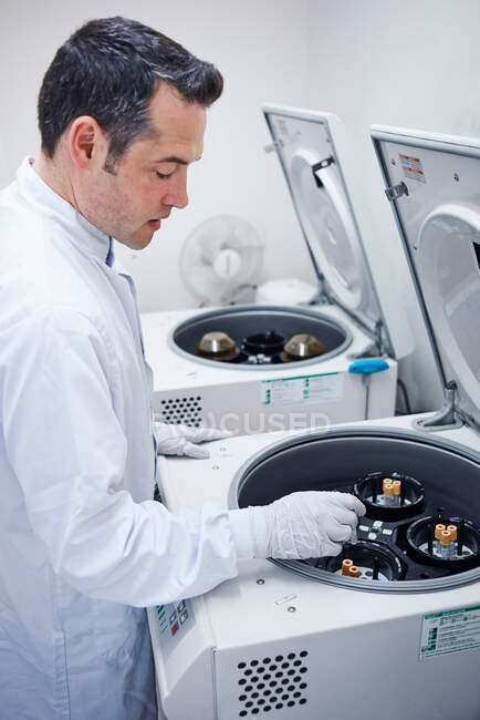Homme mettant des flacons dans la centrifugeuse — Photo de stock