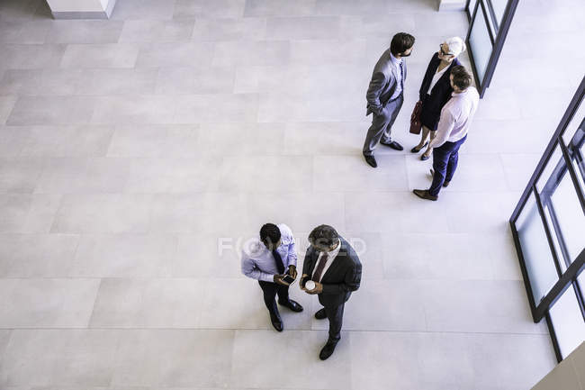 High angle view of businesswoman and businessmen having discussions in office atrium — Stock Photo