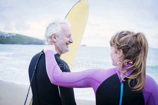 Отец и дочь с доской для серфинга на пляже — стоковое фото