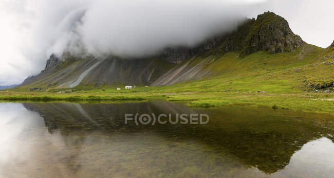 Niedrige Wolken über Bergen, die sich im Seewasser spiegeln — Stockfoto