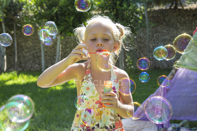 Девушка надувает пузыри на летней вечеринке в саду — стоковое фото