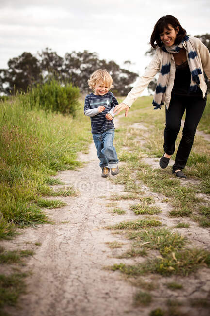 Мать и маленький сын бегут по грунтовой дорожке — стоковое фото
