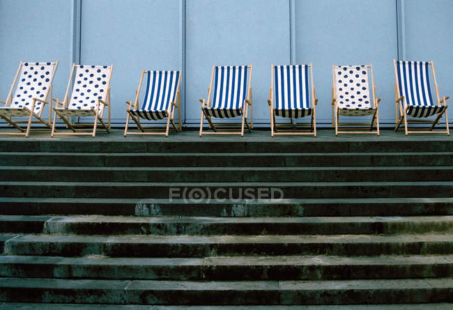 Deckchairs in a row above pool stairs — Stock Photo