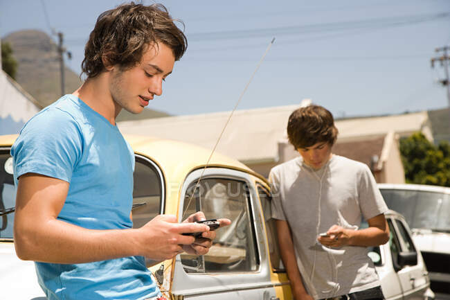 Teenage boys listening to mp3 player and playing video game — Stock Photo