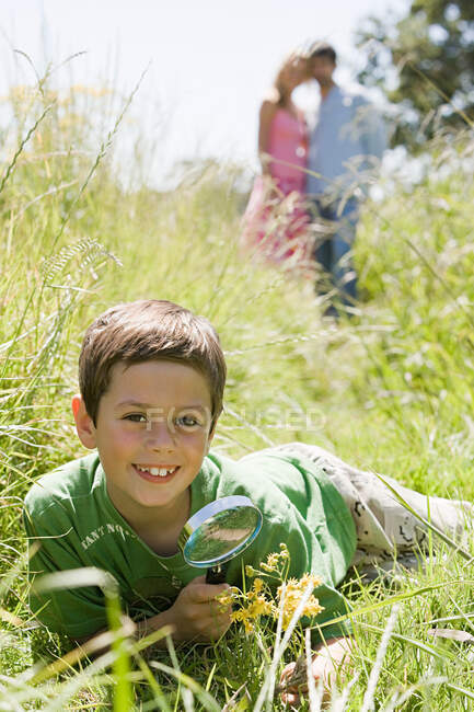 Un garçon tenant une loupe — Photo de stock