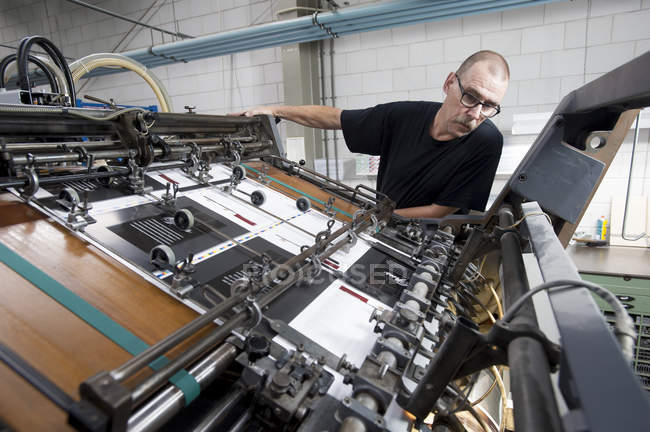 Рабочий контроль печатной машины в типографии — стоковое фото