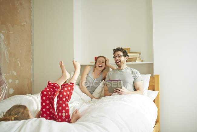 Mittleres erwachsenes Paar legt sich hin, während Tochter wieder ins Bett fällt — Stockfoto