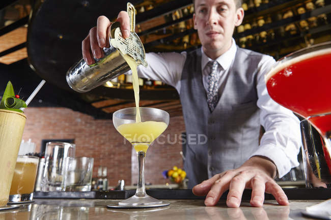 Camarero caucásico verter cóctel en el bar - foto de stock