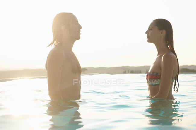 Casal de pé, de frente para o outro na piscina exterior — Fotografia de Stock