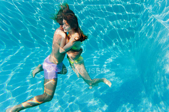 Young couple embracing in swimming pool, underwater view — Stock Photo