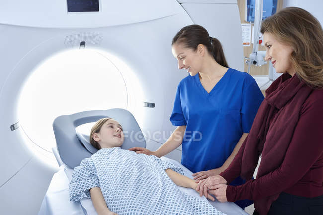 Radiografo e madre rassicurante ragazza che entra nello scanner CT — Foto stock
