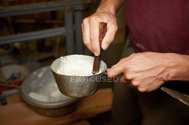 Обрезанное изображение рабочего, помешивающего горшок в магазине — стоковое фото