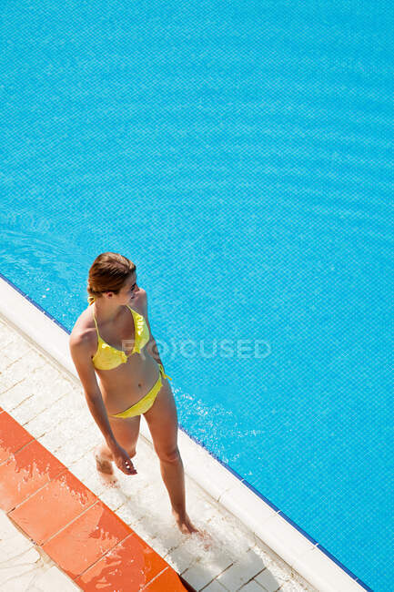 Jovem mulher andando à beira da piscina — Fotografia de Stock