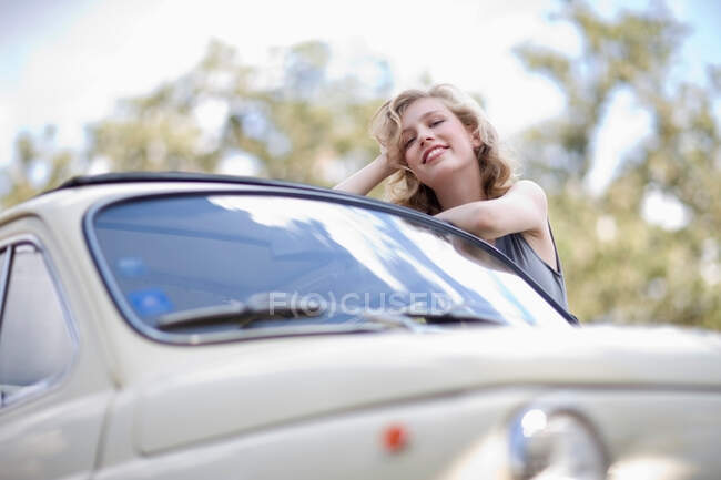 Mujer apoyada en un coche - foto de stock