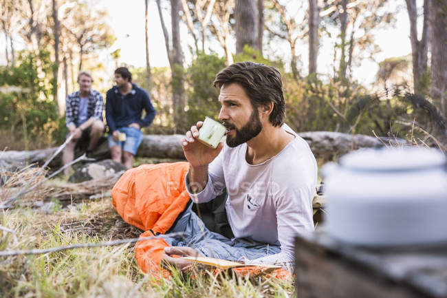 Mann im Schlafsack trinkt Kaffee, Wildpark, Kapstadt, Südafrika — Stockfoto