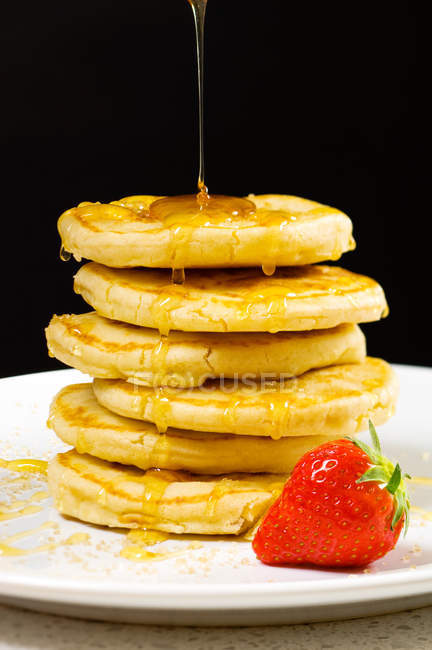 Honey pouring on pancakes — Stock Photo
