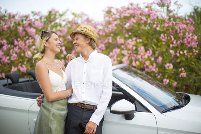 Young couple leaning against convertible by blossoms, Majorca, Spain — Stock Photo