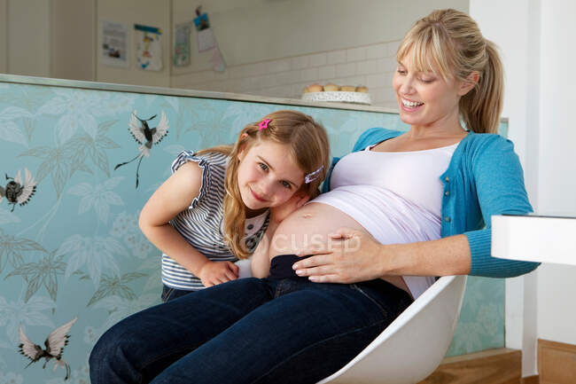Una joven madre embarazada con su hija - foto de stock