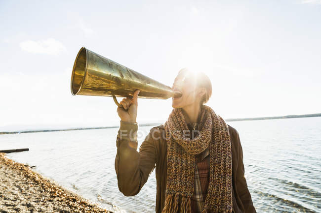 Молода жінка використовує мегафон біля озера — стокове фото