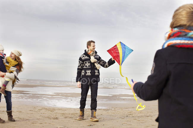 Padres adultos con hijo e hija jugando con cometa en la playa, Bloemendaal aan Zee, Países Bajos - foto de stock