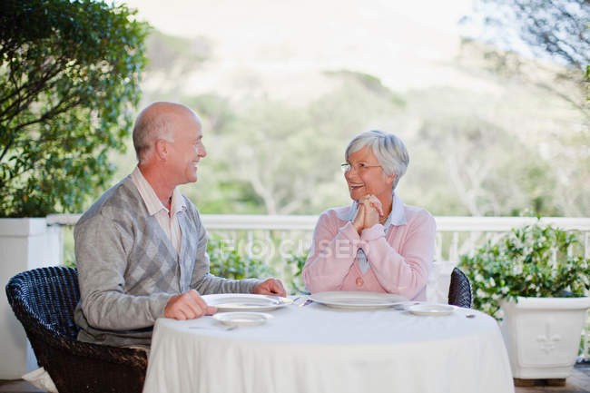 Старшая пара, сидящая за столом на открытом воздухе — стоковое фото