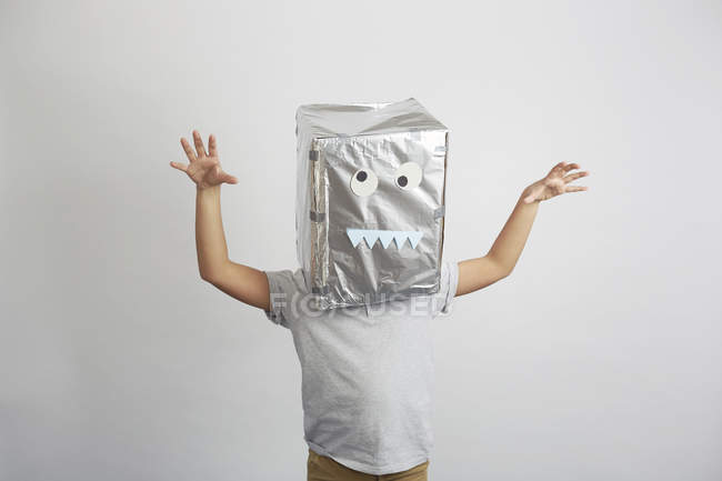 Мальчик с серебряной коробкой на голове, смешное лицо на коробке — стоковое фото