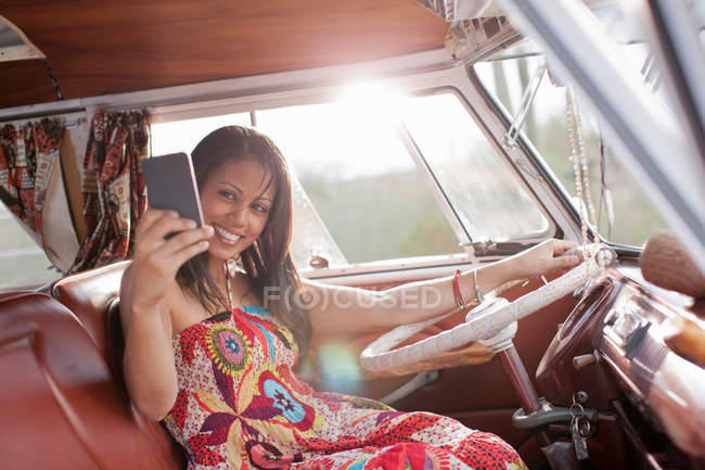 Jovem usando telefone celular em van campista, sorrindo — Fotografia de Stock