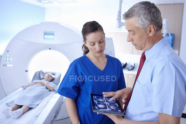 Menina em tomógrafo, médico e radiologista olhando para a varredura em tablet digital — Fotografia de Stock