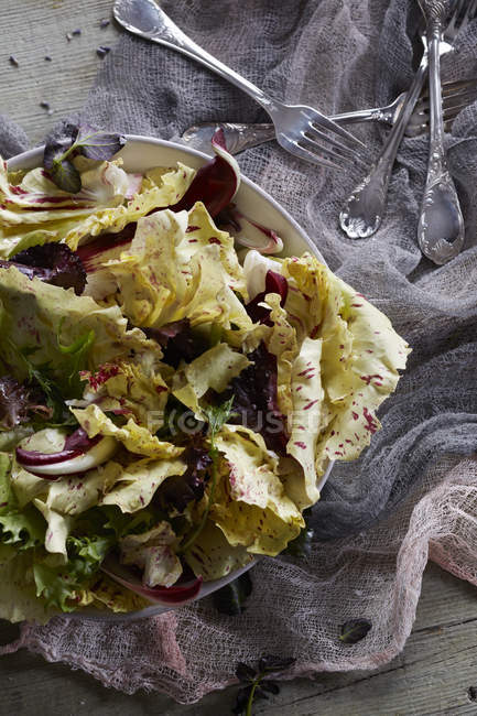 Still life with yellow radicchio salad and cutlery — Stock Photo