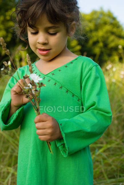 Une fille tenant un tas de fleurs sauvages — Photo de stock