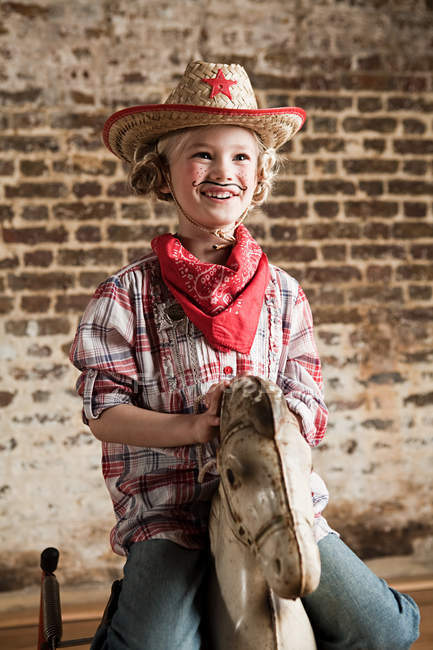 Giovane ragazza vestita da cowgirl con cavallo a dondolo — Foto stock