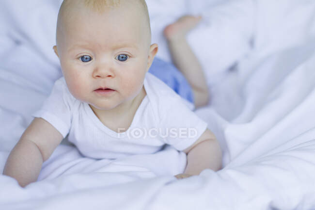Baby girl lying on bedclothes — Stock Photo